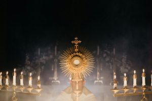 Priest holding the monstrance with incense clouds