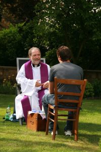 Priest hearing a man's confession outside